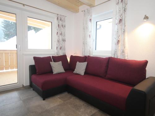 a red couch in a room with two windows at Charming Apartment in Kirchberg in Tirol with Private Garden in Kirchberg in Tirol