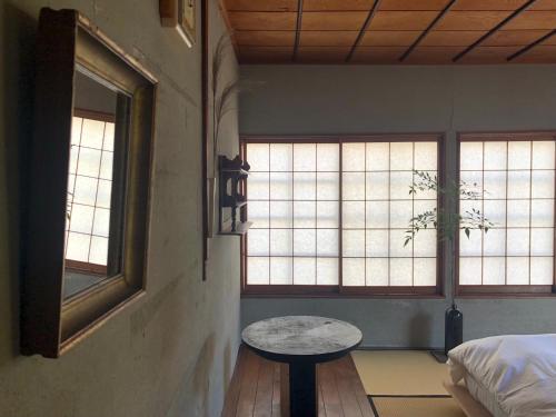 Machiya Guest House Carta في كانازاوا: غرفة بها نافذتين وطاولة فيها
