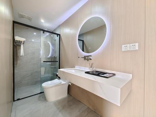 een badkamer met een wastafel, een toilet en een spiegel bij Airport Dream B&B - Tianfu International Airport Branch in Jianyang