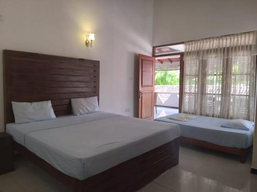 a bedroom with two beds and a large window at Pahalage Guesthouse in Beruwala
