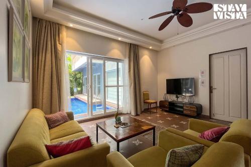a living room with a couch and a tv at StayVista at Villa Amethyst with Pvt Pool & Jacuzzi in Saligao