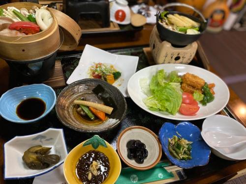 a table with plates of food and bowls of food at Tabinoyado Saikawa in Kuroishi