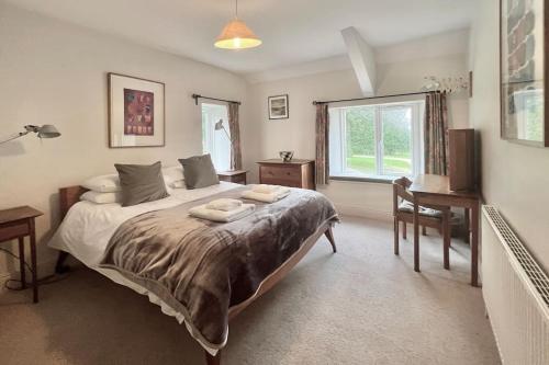 a bedroom with a bed with a desk and a window at Stable Corner, a 4 bedroom rural retreat in Loddiswell