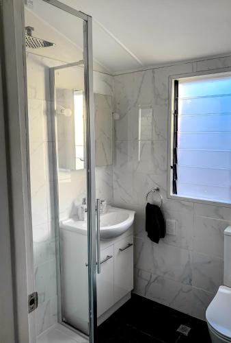 a white bathroom with a sink and a shower at West End Studio 3 in Brisbane