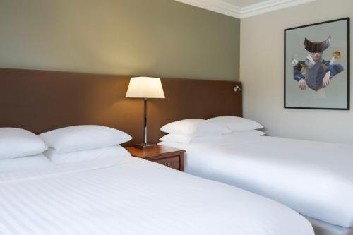 two beds in a hotel room with white pillows at Delta Hotels by Marriott Huntingdon in Huntingdon