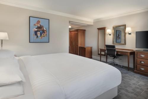 a hotel room with a large white bed and a desk at Delta Hotels by Marriott Huntingdon in Huntingdon