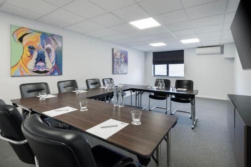 a room with tables and chairs and a painting of a dog at Delta Hotels by Marriott Huntingdon in Huntingdon