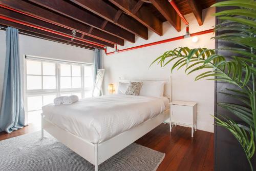 um quarto com uma cama branca e uma planta em Jarrah Loftprime Location Freo Warehouse em Fremantle