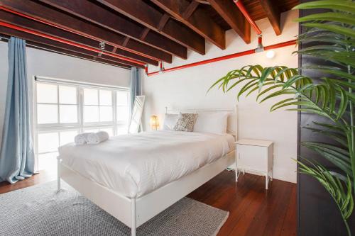 Un dormitorio con una cama blanca y una planta en Jarrah Loftprime Location Freo Warehouse en Fremantle