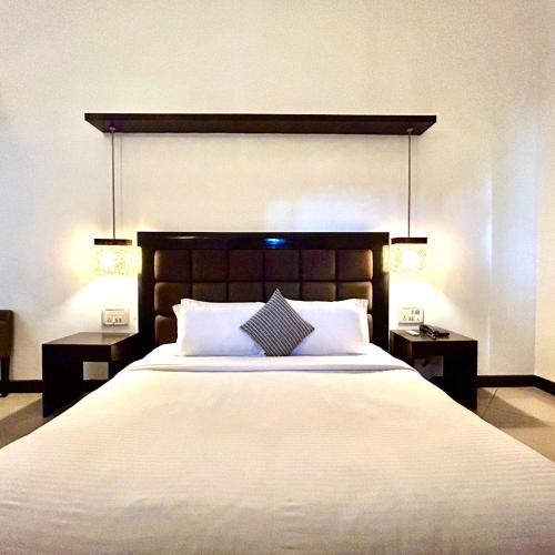 a bedroom with a large white bed with two night stands at Casabela Boutique Hotel in Porvorim