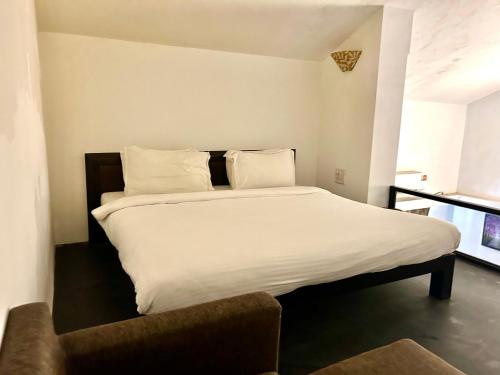 a bed with white sheets and pillows in a room at Casabela Boutique Hotel in Porvorim