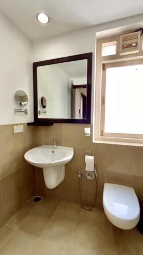 a bathroom with a sink and a toilet and a mirror at Casabela Boutique Hotel in Porvorim