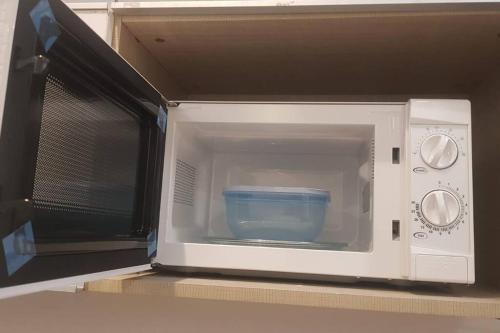 eine Mikrowelle mit einer blauen Schüssel darin in der Unterkunft Darshana Studios -Feel the luxury fully furnished in Noida