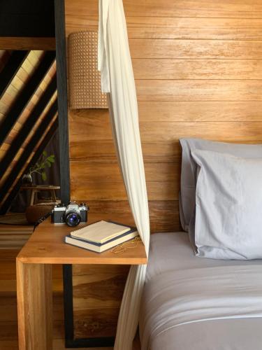 a table with a camera and a book on a bed at Desa Cabins in Balian