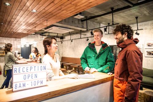 a group of people standing around a counter with a sign at Ten to Ten Hostel in Sapporo