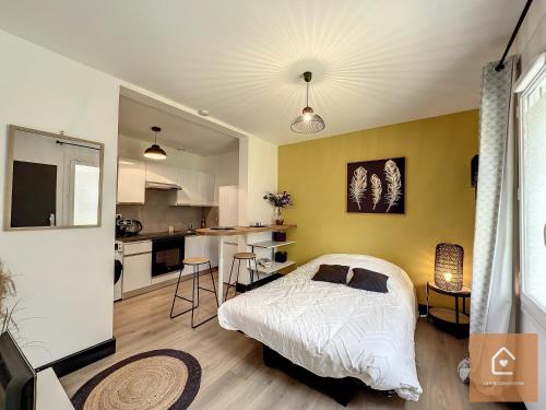 een slaapkamer met een wit bed en een keuken bij Yellow Studio - Arrivée Autonome in Châtellerault