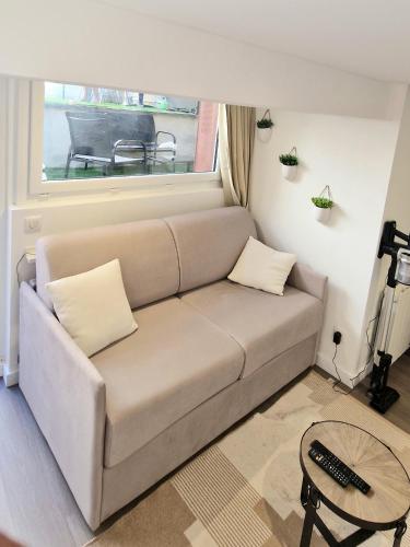 un sofá en una sala de estar con ventana en Studio terrasse en Le Cendre