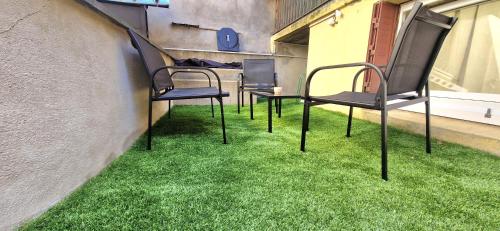 trois chaises assises sur l'herbe à côté d'un bâtiment dans l'établissement Studio terrasse, à Le Cendre