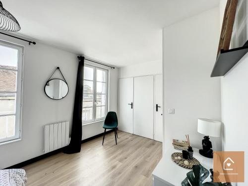 a white living room with a chair and a window at Bienvenue chez Noémie - Arrivée Autonome in Châtellerault