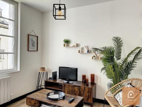 a living room with a tv and a wooden table at Bienvenue chez Noémie - Arrivée Autonome in Châtellerault