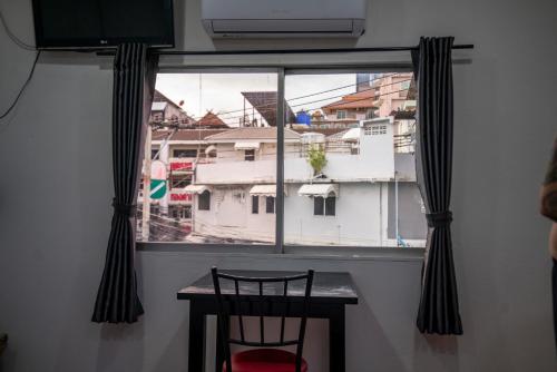 a window with a table and a chair in a room at Splash Bar and Guesthouse in Pattaya Central