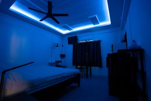 a blue room with a bed and a ceiling fan at Splash Bar and Guesthouse in Pattaya Central