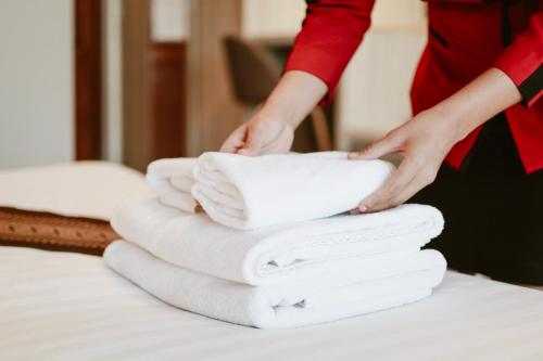 kobieta kładąca białe ręczniki na łóżku w obiekcie Tubtim Siam Suvarnabhumi Hotel w mieście Bang Phli