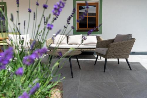 a patio with a couch and chairs and purple flowers at Gaestehaus Berger in Sankt Jakob in Defereggen