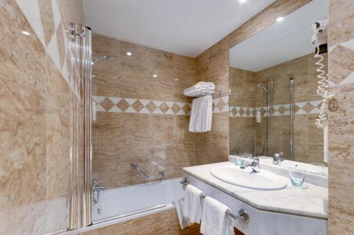 La salle de bains est pourvue d'une baignoire, d'un lavabo et d'une douche. dans l'établissement Hotel Madrid Centro, Affiliated by Meliá, à Madrid