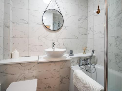 a bathroom with a sink and a mirror and a tub at Swallow Cottage in Llandwrog