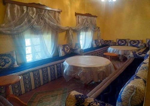 ein Wohnzimmer mit 2 Tischen und Vorhängen in der Unterkunft Auberge Jbel Raids in Tagoudit