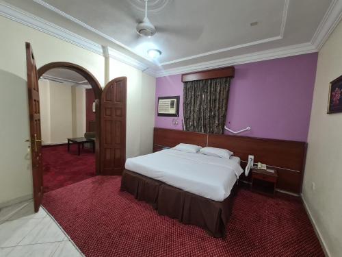 a bedroom with a bed and a purple wall at شقق درة الصالحين in Makkah