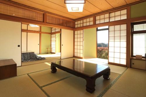 Zimmer mit einem Tisch in einem Zimmer mit Fenstern in der Unterkunft Gentou - Vacation STAY 28719v in Aso