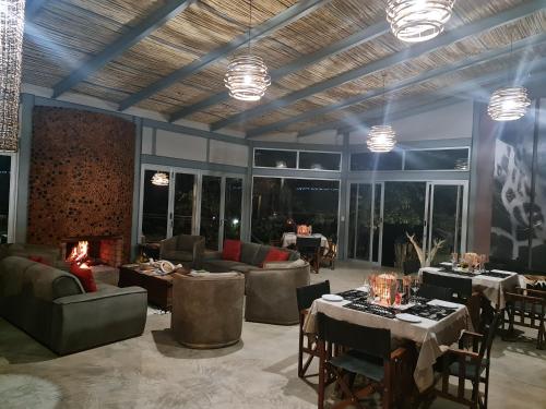 a living room with tables and couches and windows at Mountain Peak Game Lodge and Camping in Ozongaka