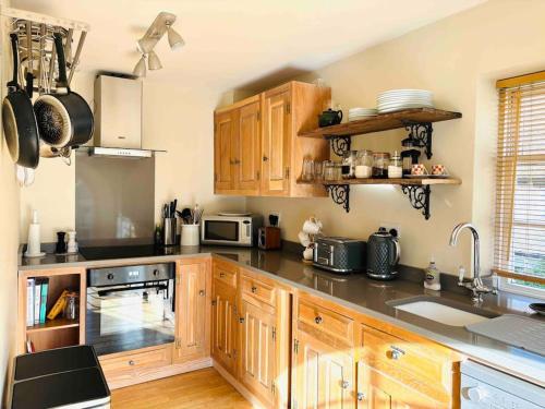 cocina con armarios de madera y encimera en 3 bedroom converted chapel in historic Oundle, en Oundle