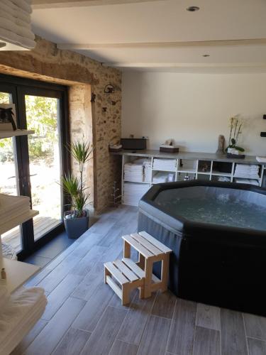 a hot tub in a room with a table and a bench at au grain de folie in Lubersac