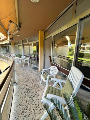a screened porch with white chairs and windows at Appartement Nice aéroport seafront with pool in Cros-de-Cagnes