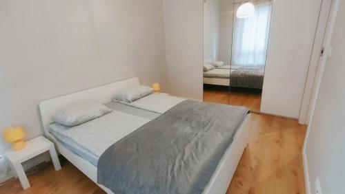 FIRST -- Green Żoliborz Apartment 4 في وارسو: غرفة نوم بيضاء صغيرة مع سرير ومرآة