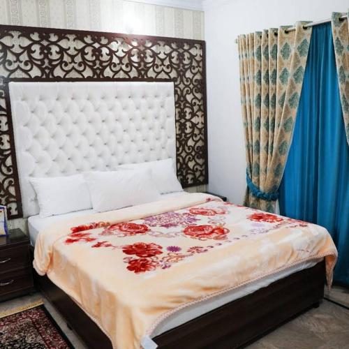 een slaapkamer met een groot bed met rode bloemen erop bij Bodla Royal Hotel in Multan