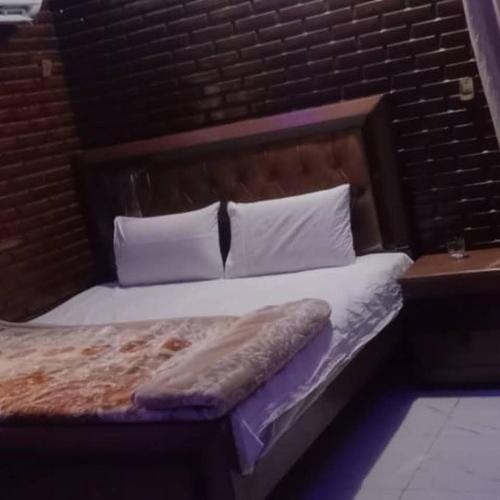een bed met een houten hoofdeinde en witte kussens bij Bodla Royal Hotel in Multan