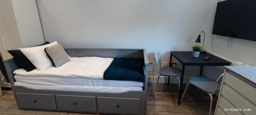 a bed in a small room with a desk and a table at Studio Flat / London Gateway in Borehamwood