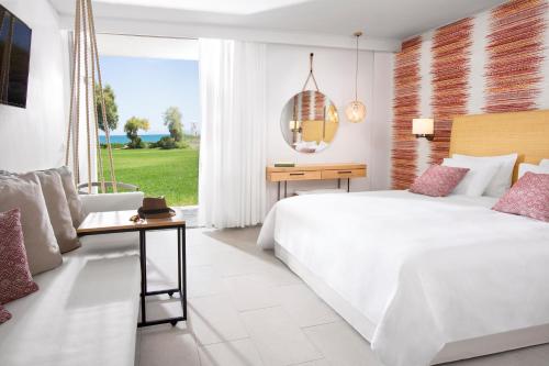 a bedroom with a large white bed and a window at Agapi Beach Resort Premium All Inclusive in Amoudara Herakliou