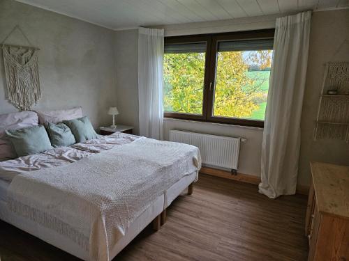 a bedroom with a large bed and a large window at Ferienhaus im Grünen in Morbach