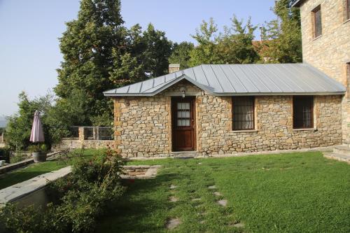 a stone house with a grass yard in front of it at Guesthouse Kontogianni - Materka in Nymfaio