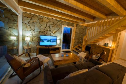 uma sala de estar com um sofá, uma mesa e uma televisão em Chalet proche des pistes de ski avec vue et spa em Gérardmer