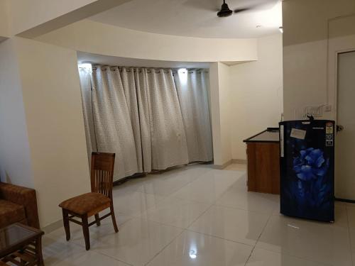 - un salon avec un réfrigérateur, une table et des chaises dans l'établissement Hotel Charaksanjivani, à Navi Mumbai