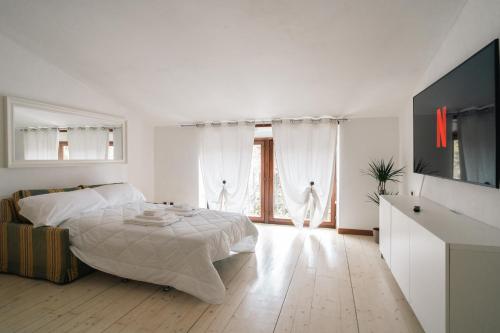 ヴェローナにあるAppartamento Scaligero Borgo Trentoの白いベッドルーム(ベッド1台、大きな窓付)