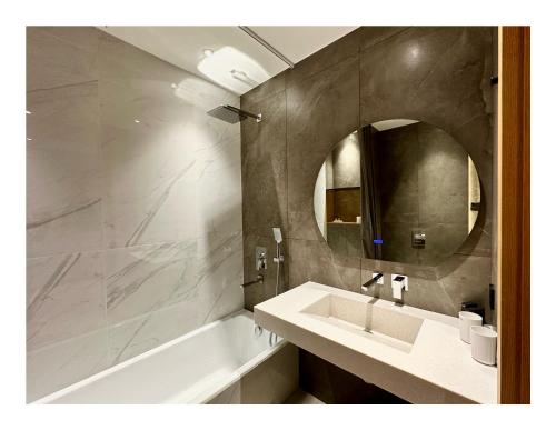 a bathroom with a sink and a tub and a mirror at Deluxe Apartment in Tashkent