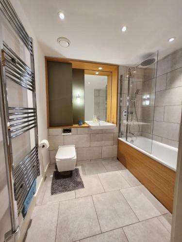 a bathroom with a toilet and a tub and a sink at Kaf Luxury Apartment in London