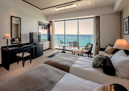 a hotel room with a large bed and a television at Hotel Monterey Okinawa Spa & Resort in Onna